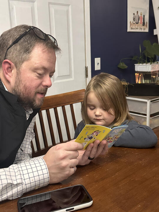 Erik reading with his young niece at the kitchen table