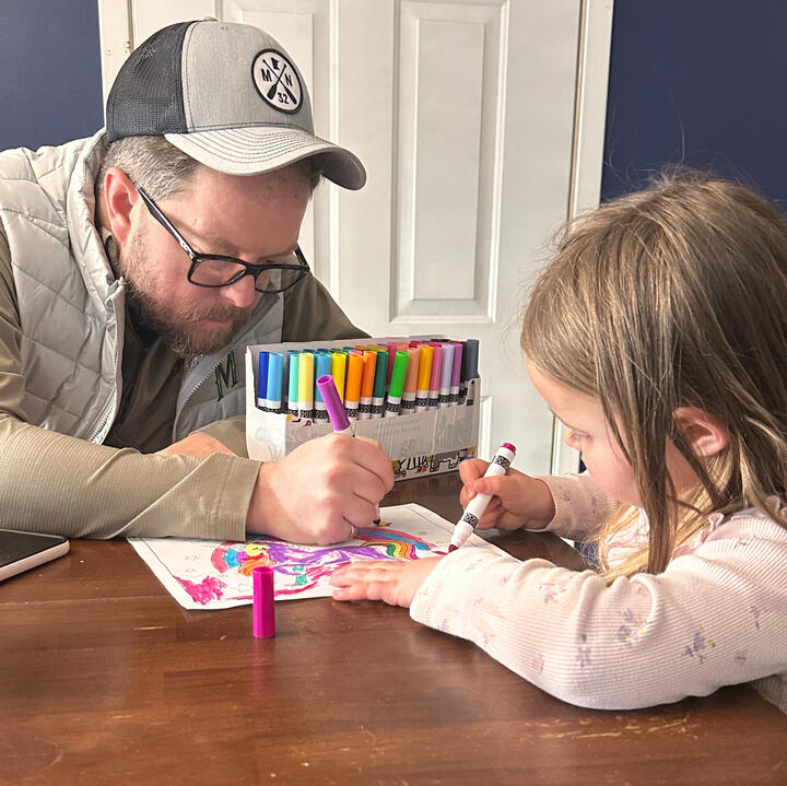Erik coloring with his young niece at the kitchen table